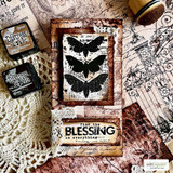 Card with the butterfly panel stamped in black on a cream frame over distressed rose paper, with two Distress ink pads and a wood-handled stamp beside it.