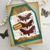 Card with the butterflies stamped in warm brown on cream inside a teal frame, with brass butterfly charms and a "BLESSINGS" tag.