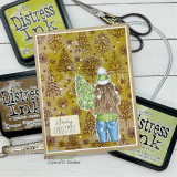 Golden pine-stamped card of the girl with the tree and 'merry christmas.'