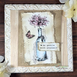 Card on a stitched linen panel with the bloom in soft pink, a blue-washed bottle, a small butterfly, and 'be gentle with yourself' on a white strip.