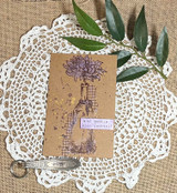 Kraft tag on a lace doily with the bloom stamped in purple tones and 'be gentle with yourself' on a lilac strip.