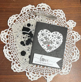 Black-and-white card with the paw heart in a die-cut heart window over a doily, script sentiment on a banner.