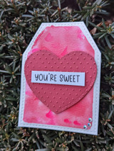 Tag card with a large embossed pink heart on a watercolor pink panel, sentiment strip "YOU'RE SWEET."