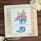 Blue rain boots full of pink roses on a pastel plaid panel, layered on cream lace paper and woodgrain, sentiment 'When life throws you a rainy day, play in the puddles'
