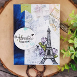 Card of the Eiffel Tower on collage paper with "Adventure beckons."