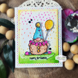 Handmade card with a hedgehog in a party hat holding a balloon and the sentiment 'Happy Birthday', over a pink and blue confetti-stenciled background.