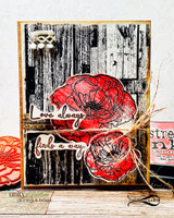 Card with two red poppies over a black and white distressed woodgrain panel with gold and raffia accents, sentiment "Love always finds a way." split across two strips.