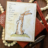 Distressed vintage card with a hand colored velveteen rabbit standing tall and a block of type about becoming real, tile texture in the background.