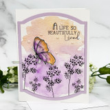 Card with a rainbow-colored butterfly over purple watercolor and stamped branches, 'A life so beautifully lived.'