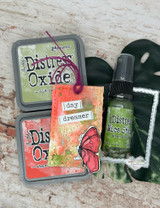 Mixed-media tag with a butterfly, 'A life so beautifully lived,' beside distress spray.