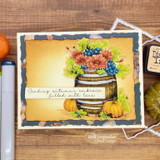 Barrel of autumn blooms on a navy-matted card, 'sending autumn's embrace, filled with love'.