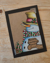 Black-framed kraft card with the tall snowman and "There's something about Christmas time"