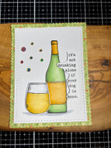 Card with a green wine bottle and glass and the 'not drinking alone' sentiment on a gridded mat.