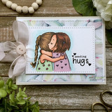 Card with two braided-hair girls hugging in pastel dresses and 'sending hugs' beside a sheer bow.