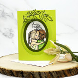 Lime card with the hugging girls in an oval frame with a leafy die-cut and 'sending hugs.'