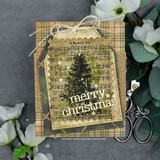 Kraft gift tag with the tree colored green over a plaid and sheet-music panel, 'merry christmas.'