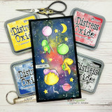 Slim card with a galaxy-blended background in purple, blue and yellow, dinosaurs on balloons and 'It's party time,' shown with distress ink pads.