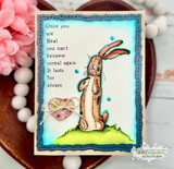 Card with the rabbit colored warmly on a bright teal-and-green grassy scene with pink blooms.