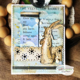 Card with the rabbit and book-page panel over a snowflake background with green ribbon.