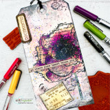 Bright mixed-media tag in purple, pink and yellow inks with the grungy flower, layered postage and a 'go where your heart takes you' banner.