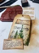 Winter dictionary-word ephemera strips beside a tag reading 'tinsel' with a pine-tree design.