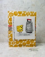 Card with a doodle border stamped along the bottom, a coloured cheese block and grater above it, sentiment "HAVE A GRATE DAY," over a gold dot background.