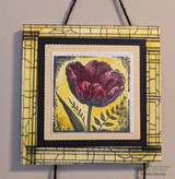 Framed art piece of a magenta tulip on a yellow crackle mat.