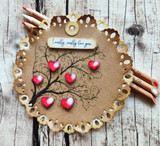 A whimsical swirled tree hung with hearts stamped in red rubber and colored on a handmade card reading "I really, really love you."