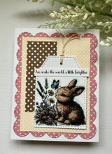 Tag card with the bunny and wildflowers over polka-dot paper: 'You make the world a little brighter.'
