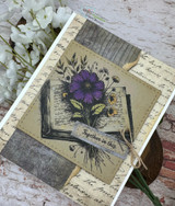The open-book bouquet in purple tones on a distressed woodgrain and ephemera card.
