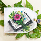 The book-and-flowers scene on a scalloped white card among green leaves.