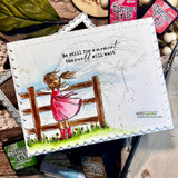 White scalloped card with the girl in a hot-pink dress and windswept hair, sentiment “Be still for a moment, the world will wait,” styled with distress ink pads.