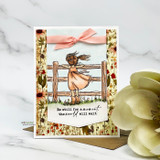 Floral-bordered card with a peach ribbon bow; the girl stands at the fence in a soft coral dress under “Be still for a moment, the world will wait.”