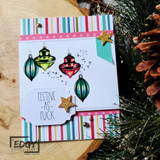 Card with three jewel-toned ornaments and a 'festive as f.' tag over striped patterned paper.