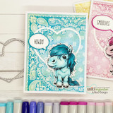 Teal pony with a 'Howdy' speech bubble on layered paisley papers next to pink and blue markers.