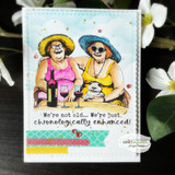 Card with Angie Blom's two mature ladies in sun hats and sunglasses sharing wine, 'We're not old... We're just chronologically enhanced.'