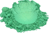 A loose mound of Enchanted Emerald mica pigment powder in a shimmering jewel green, photographed on white.
