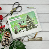 Green-blended snowy card with the stag beside inked evergreens under “WALKING IN A WINTER WONDERLAND,” styled with pinecones and berries.