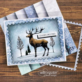 Blue speckled scalloped card with the stag in a snowy tree line and a “SEASON'S GREETINGS” label, layered on winter papers.