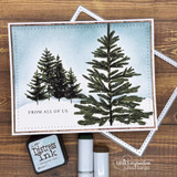 Snowy scene card of two inked evergreen pines under a soft blue sky, 'from all of us' sentiment