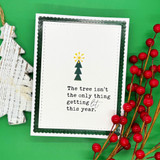 Clean white card on a green backdrop: one tiny stamped pine tree topped with a yellow star above “The tree isn't the only thing getting lit this year.”