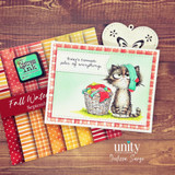 The Fall Watercolor Splendor 6x6 sheets fanned out in red, orange and yellow stripes, dots and gingham, with a finished card of a grumpy cat beside a laundry basket resting on top.