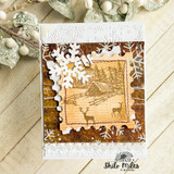Snowflake-embossed card with the cabin scene stamped in brown on burnt paper, framed like a window.