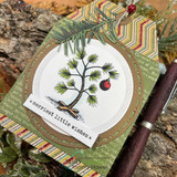 Card with the pine tree in a circle frame on woodgrain, captioned 'merriest little wishes.'