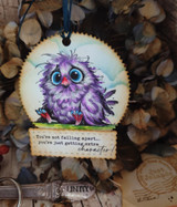 Round wood ornament with a purple-toned owl and "You're not falling apart, you're just getting extra character"