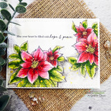 Card on burlap with two red poinsettias flanking “May your heart be filled with hope & peace.”