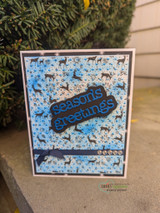 Blue card with the Frost & Fawn woodland background behind a 'Season's Greetings' die-cut.