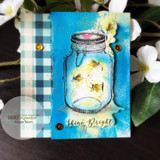 Blue mixed-media card of the glowing firefly jar with 'Shine Bright.'