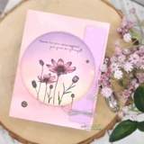Soft pink card with delicate wildflowers in a circle and a thank-you sentiment, fresh blooms beside it