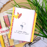 Card with a tiny black cat and 'i love you (even when you are an asshole)' on a yellow and red layout.